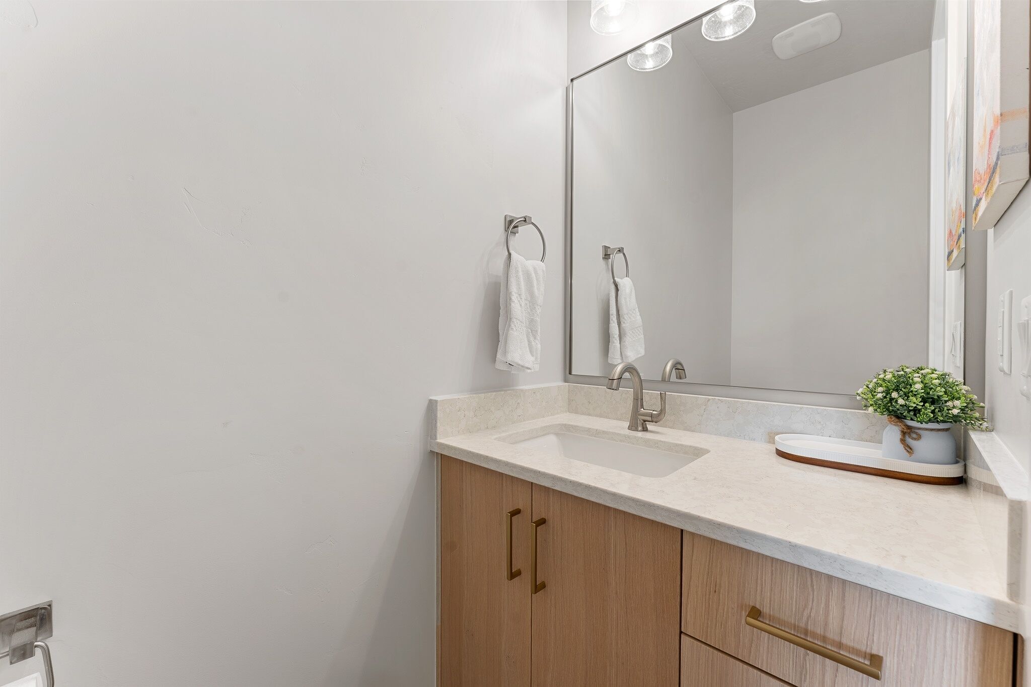 Un baño con lavabo, espejo y armarios de madera.