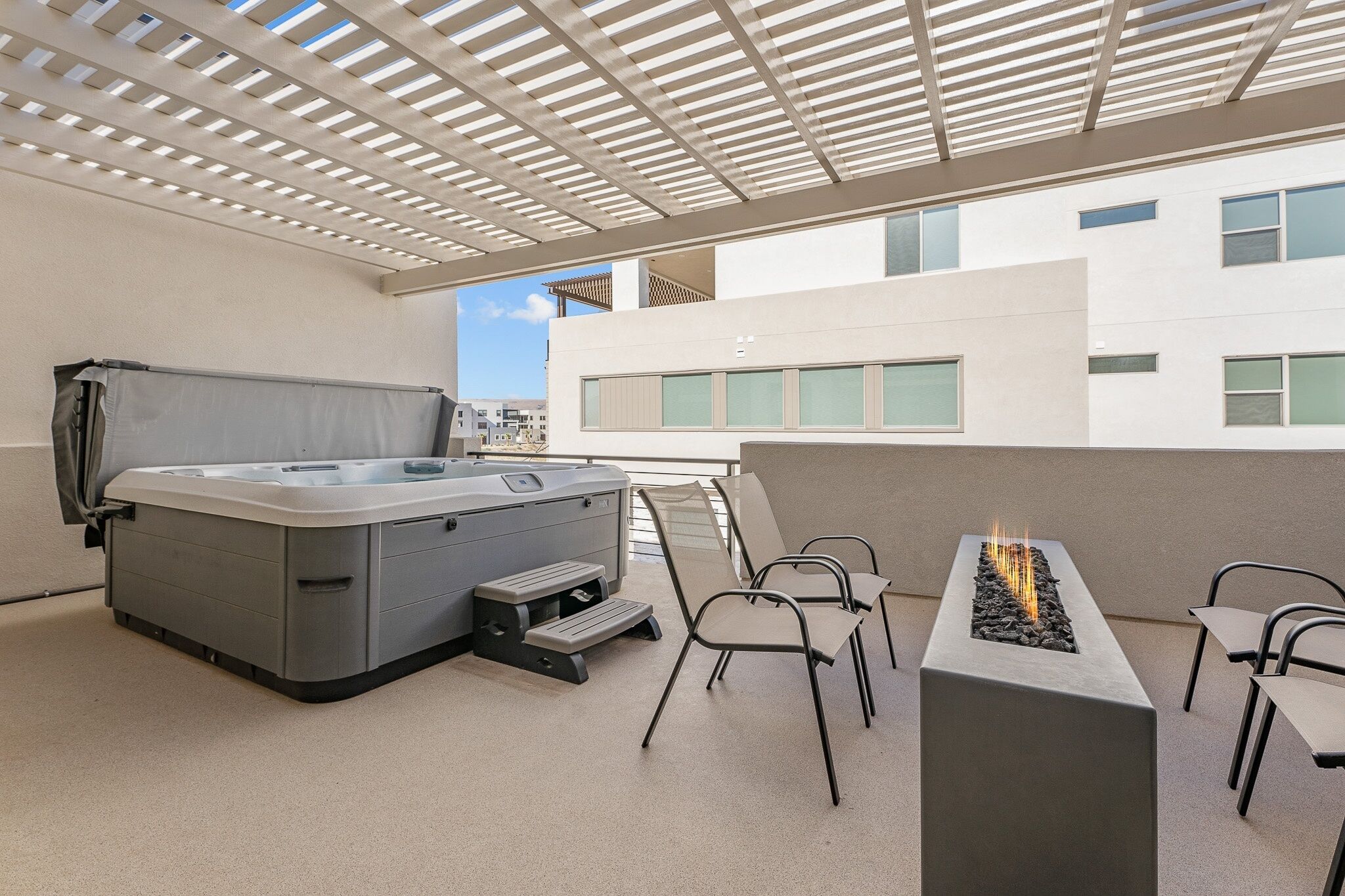 A rooftop patio with a hot tub, seating area, and a fire feature.