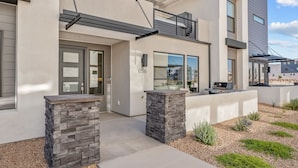A modern two-story building with a flat roof, large windows, and a stone pillar in the entrance. - Desert Family Fun 4 Bedroom Townhouse (St. George)