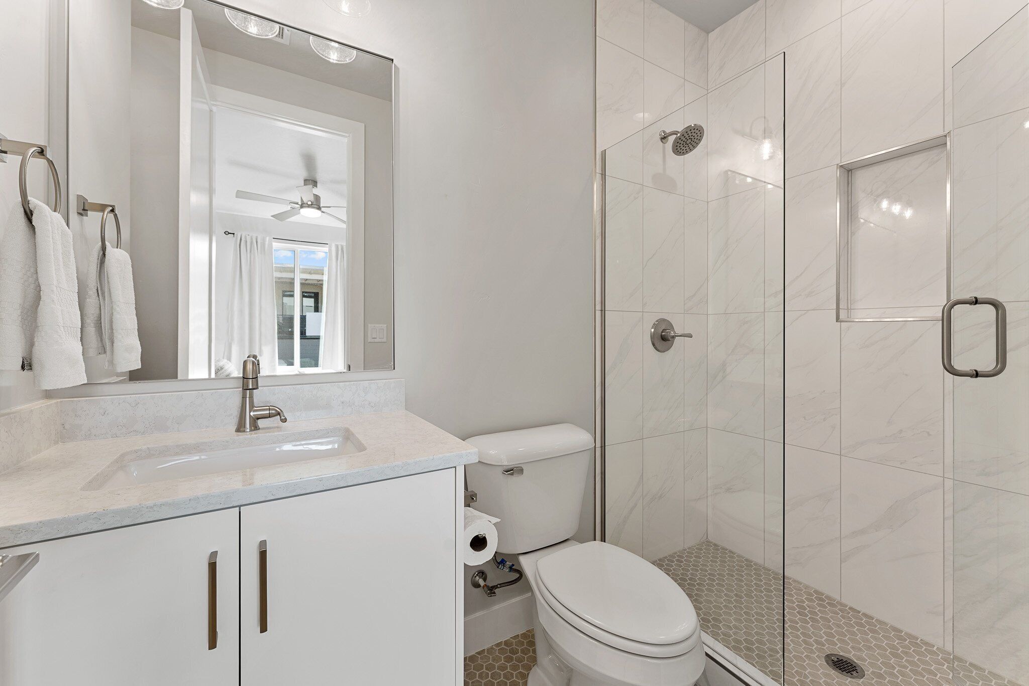Een moderne badkamer met een wit wastafel, toilet en douche.