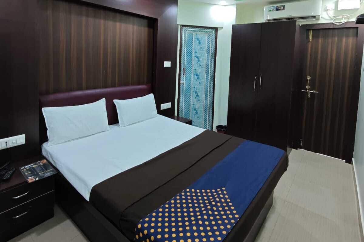 Une chambre d’hôtel moderne avec un grand lit, une armoire en bois foncé et un ventilateur de plafond.