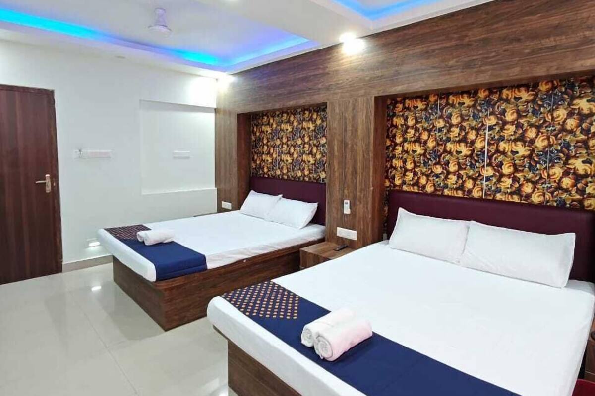 Une chambre d’hôtel avec deux lits, un ventilateur de plafond et un panneau décoratif mural.