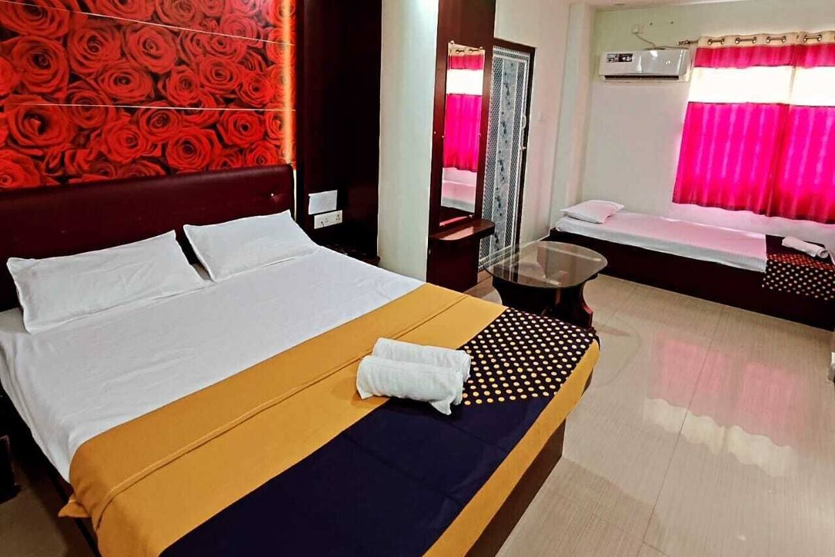 Une chambre d’hôtel avec un grand lit, une table de massage et un mur orné d’un motif de roses.