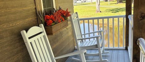 A porch with two rocking chairs and a black object on the floor.