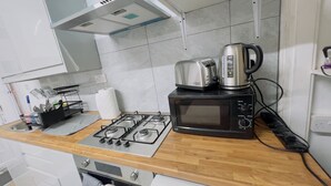 A kitchen with a gas stove, a microwave, a toaster, and a kettle. - Mcrshared House-big Bedroom Sleeps 3 (Manchester)