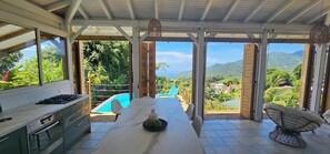 A kitchen with a marble countertop, a gas stove, and a view of a pool and mountains.
