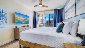 Ett hotellrum med en säng, en takfläkt, en tv och utsikt över stranden.