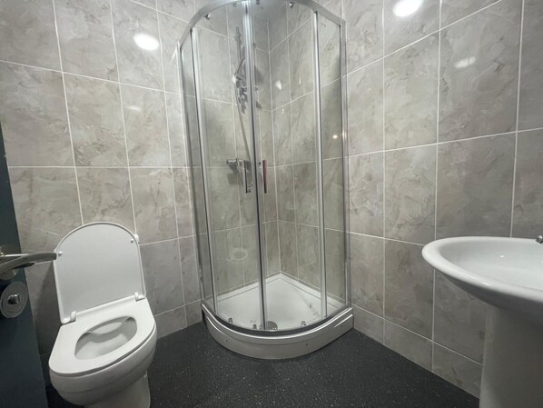 A bathroom with a glass-enclosed shower, a toilet, and a sink. - Winners Inn - Modern 1BR Cozy Retreat - Free Parking (Ashton-under-Lyne)