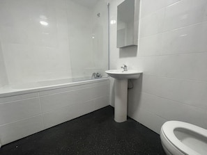 A bathroom with a bathtub, a sink, and a toilet. - Winners Inn - Modern 1BR Cozy Retreat - Free Parking (Ashton-under-Lyne)