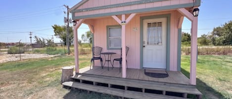 A pink building with a porch, two chairs, and a table.