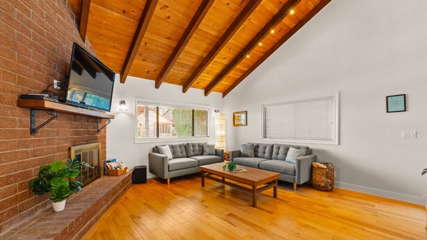 A spacious living room with a wooden ceiling, two grey sofas, a wooden coffee table, and a brick fireplace. - Perfect For Families, Walk To Beach, Rooftop Deck* (Oxnard)