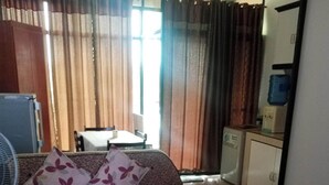 Una sala de estar con un sofá, una mesa redonda de centro, un ventilador y una cocina al fondo.
