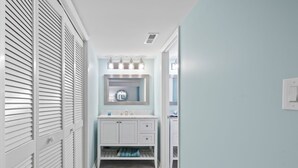 A narrow hallway with a white vanity and a mirror above it. - Bright & Spacious Direct Oceanfront 3BR Condo in North Myrtle Beach! (North Myrtle Beach)