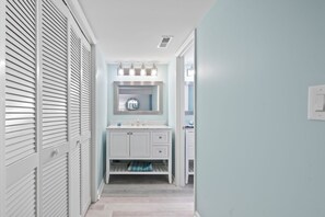 A narrow hallway with a white vanity and a mirror above it.