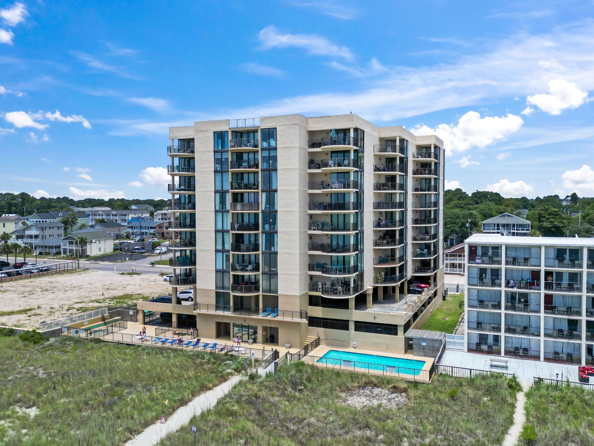 A multi-story hotel with balconies, a swimming pool, and a view of the surrounding area.