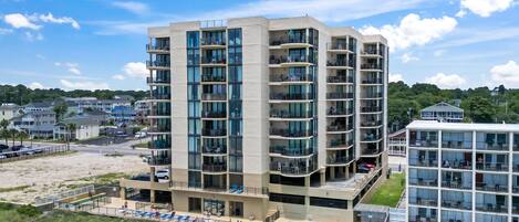 A multi-story hotel with balconies, a swimming pool, and a view of the surrounding area.