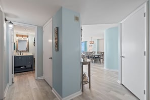 Un couloir mène à une salle à manger offrant une vue agréable, avec des murs bleu clair et un plancher en bois.