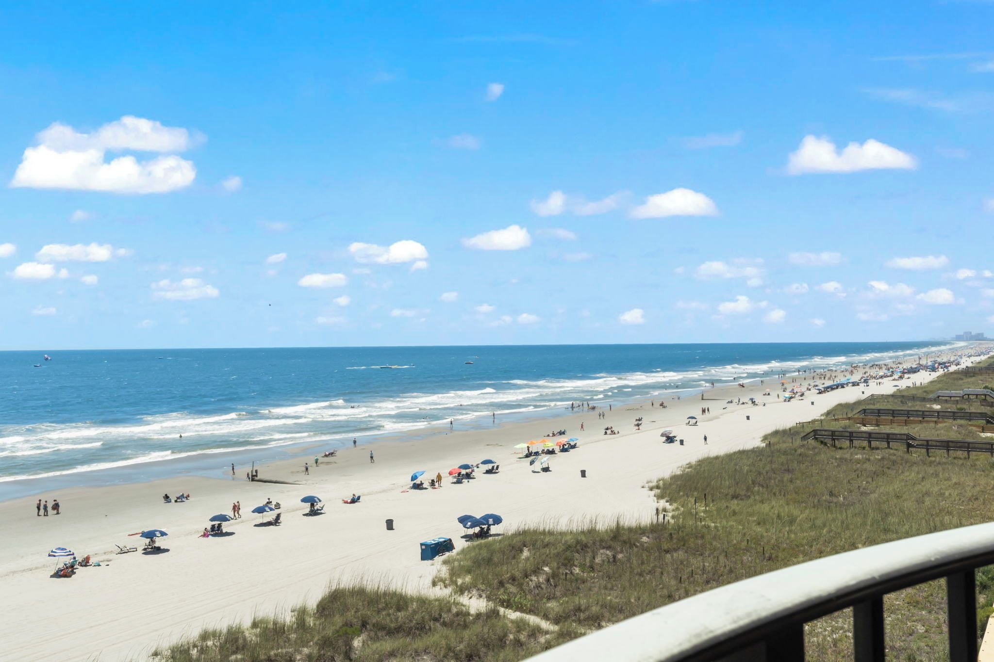 A beach with umbrellas and people, a clear sky, and the ocean.