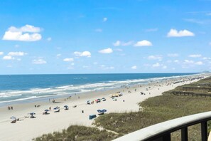 A beach with umbrellas and people, a clear sky, and the ocean. - Bright & Spacious Direct Oceanfront 3BR Condo in North Myrtle Beach! (North Myrtle Beach)