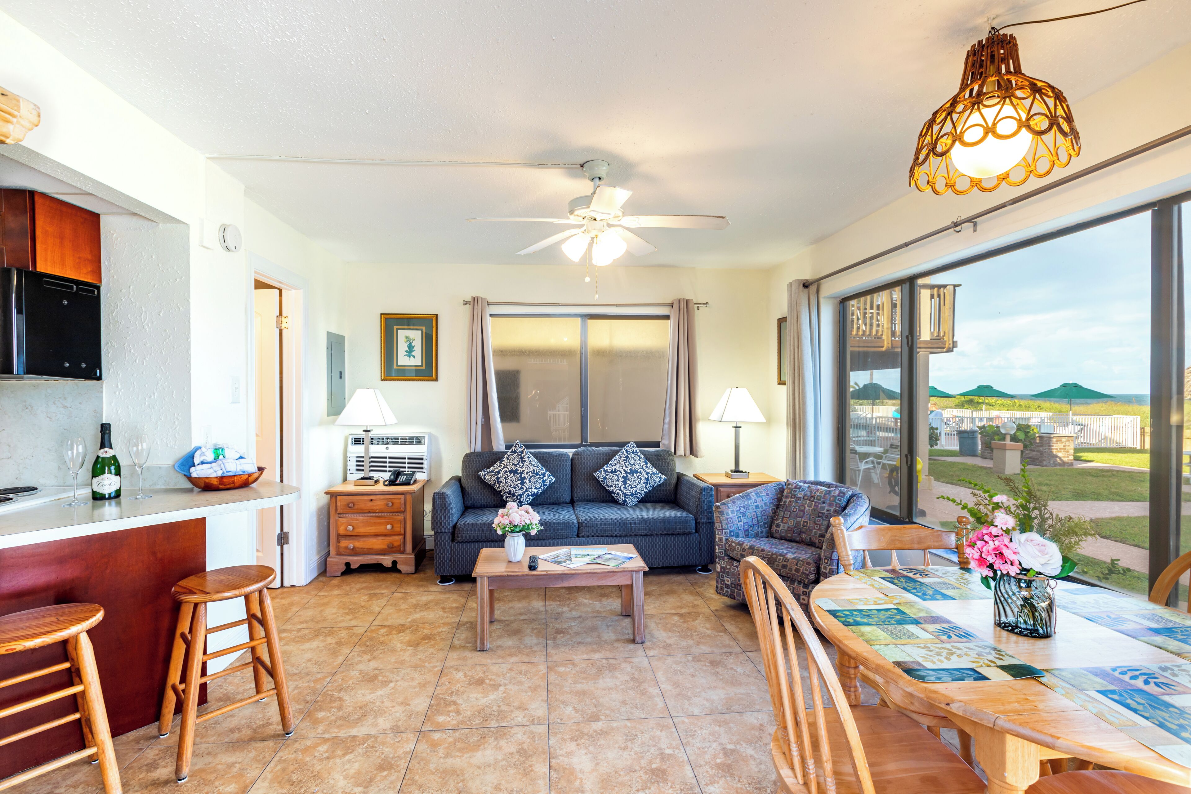 A spacious living area with a kitchen, a dining table, and a large window offering a view of the outdoors.