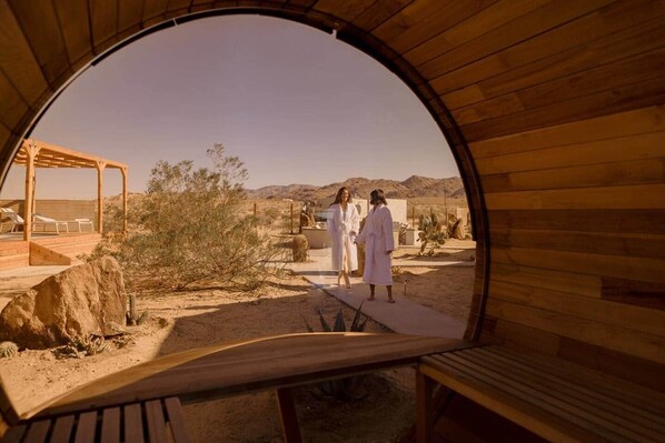 A circular wooden structure with a view of a desert landscape, a wooden bench, and a covered seating area.