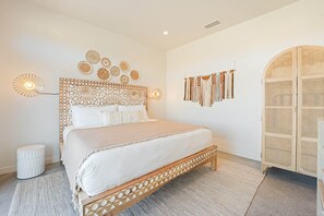 Ein Schlafzimmer mit einem Bett, einer Wandleuchte und einem Rattanschränkchen.