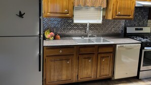 Una cocina con armarios de madera, un refrigerador de acero inoxidable, un lavamanos y un lavavajillas.
