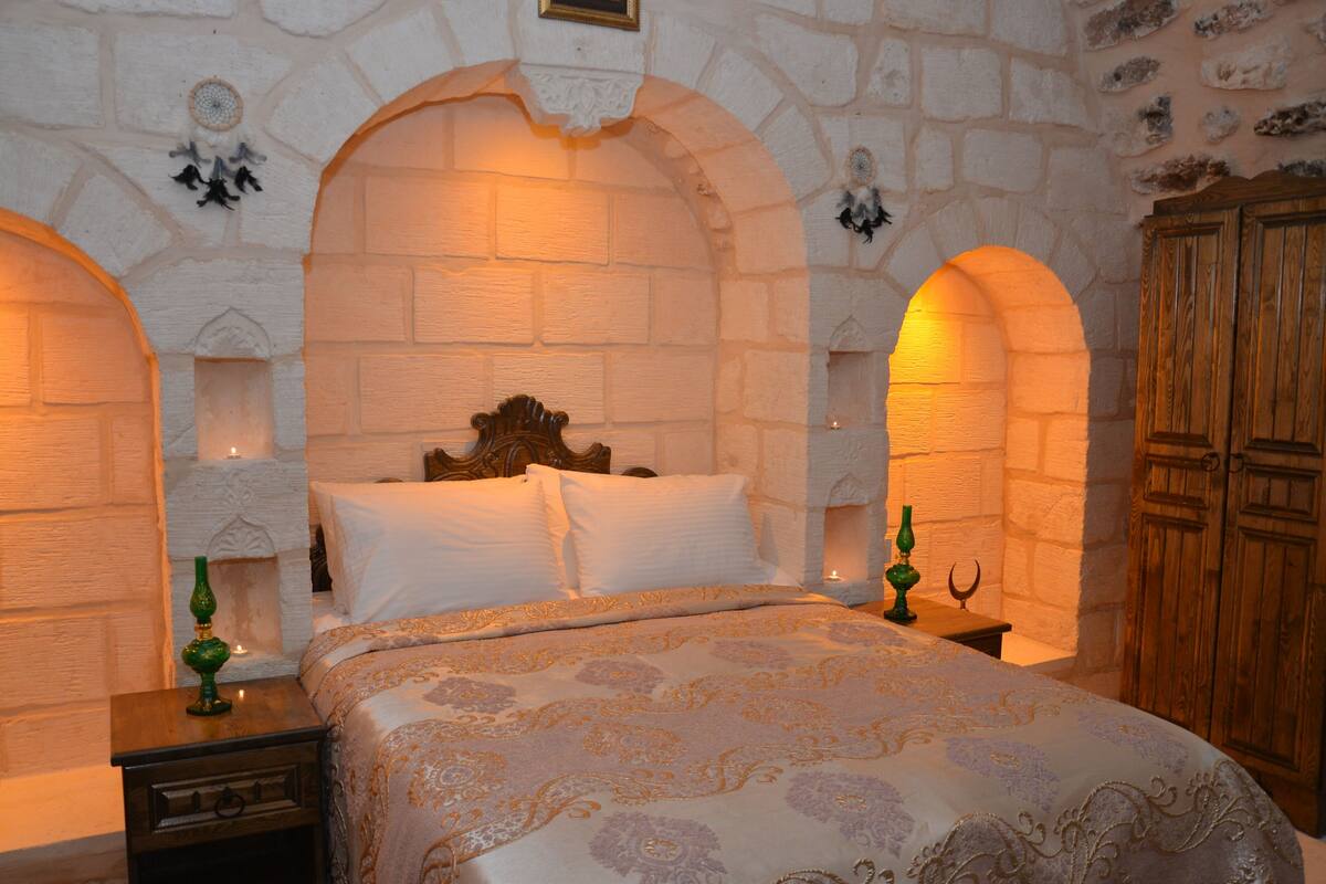 Una habitación con pared de piedra, cama de madera y armario de madera.