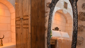 A room with a wooden wardrobe, a bed with a patterned bedspread, and a mirror with ornate designs. - Mehmet Bey Konağı Butik Otel (Midyat)