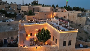 A rooftop terrace with outdoor seating and a view of the cityscape. - Mehmet Bey Konağı Butik Otel (Midyat)