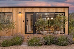 Una casa moderna de madera con grandes puertas de vidrio, un jardín de lavanda y vistas del paisaje circundante.
