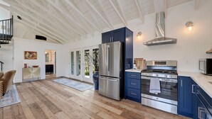 Une cuisine spacieuse dotée d’un plancher en bois, d’appareils électroménagers en acier inoxydable et d’armoires bleues.