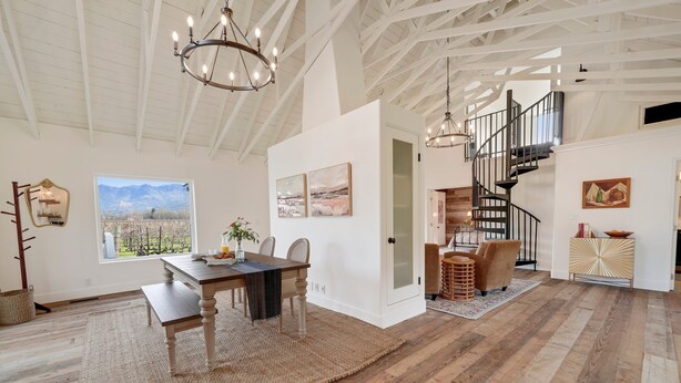 Une pièce spacieuse avec une table à manger en bois, un lustre et un escalier menant à un niveau supérieur.