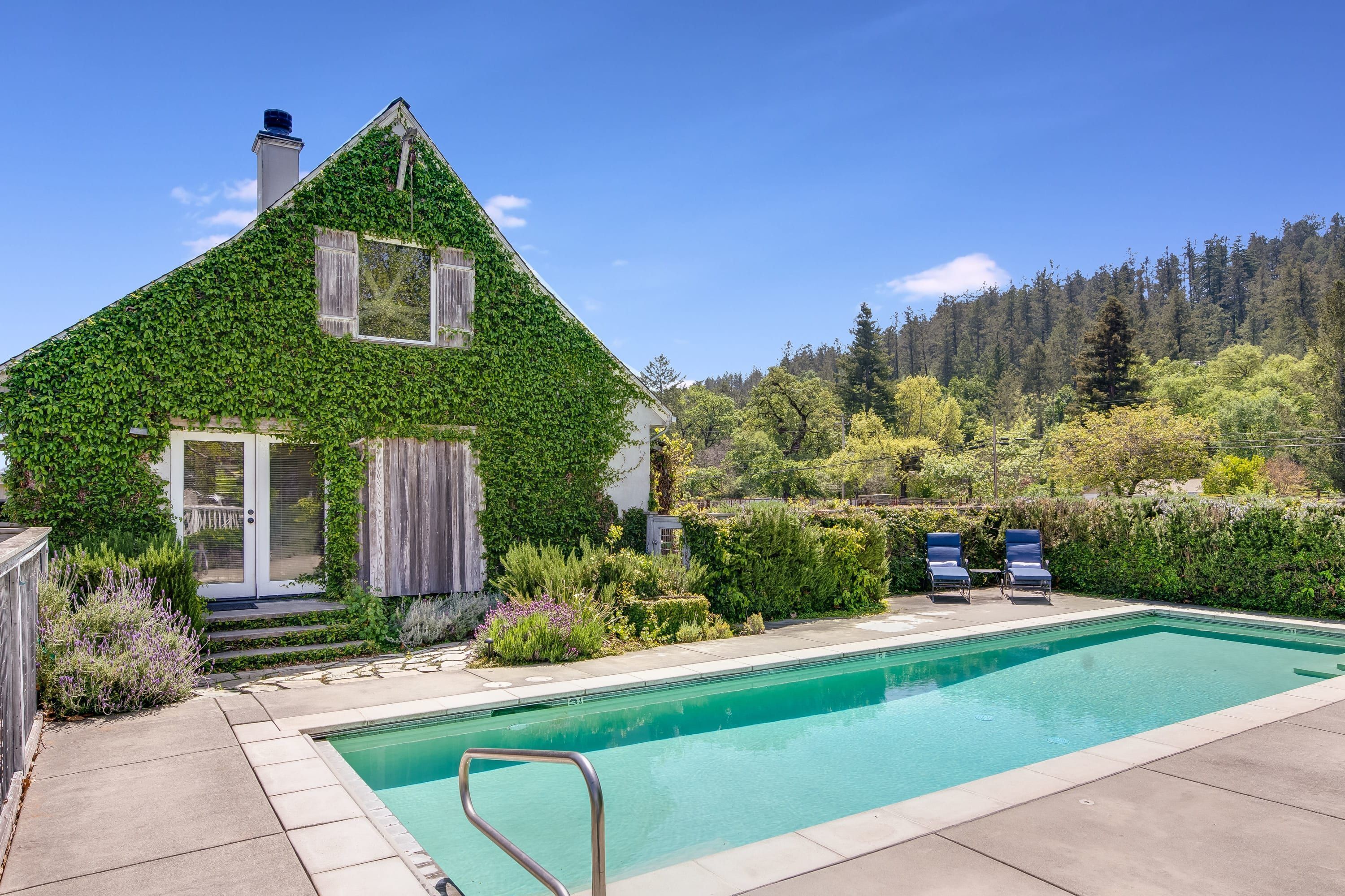 Una casa con piscina, rodeada de exuberante vegetación y un paisaje boscoso.