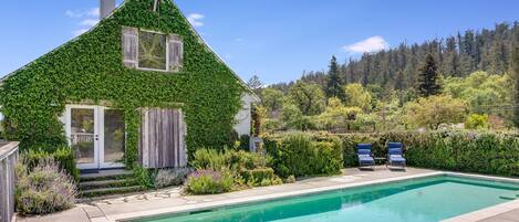 Una casa con piscina, rodeada de exuberante vegetación y un paisaje boscoso.