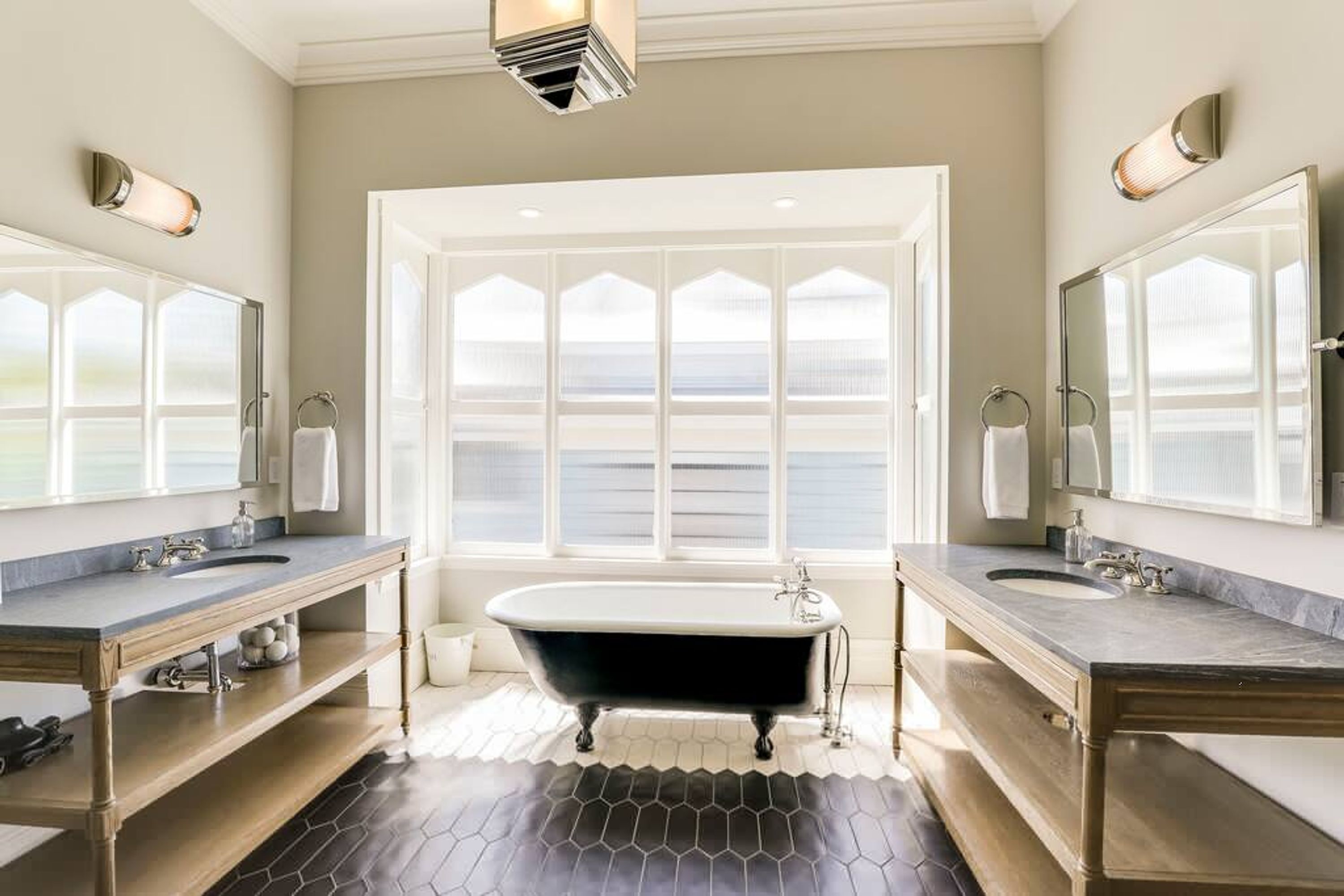 Une salle de bain avec une baignoire sur pieds, deux lavabos et de grands miroirs.