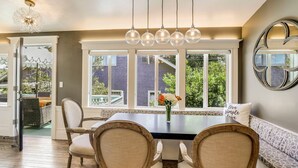 A dining area with a large table, four chairs, a chandelier, and a view through large windows. - Casa Rosa in St Helena (St. Helena)