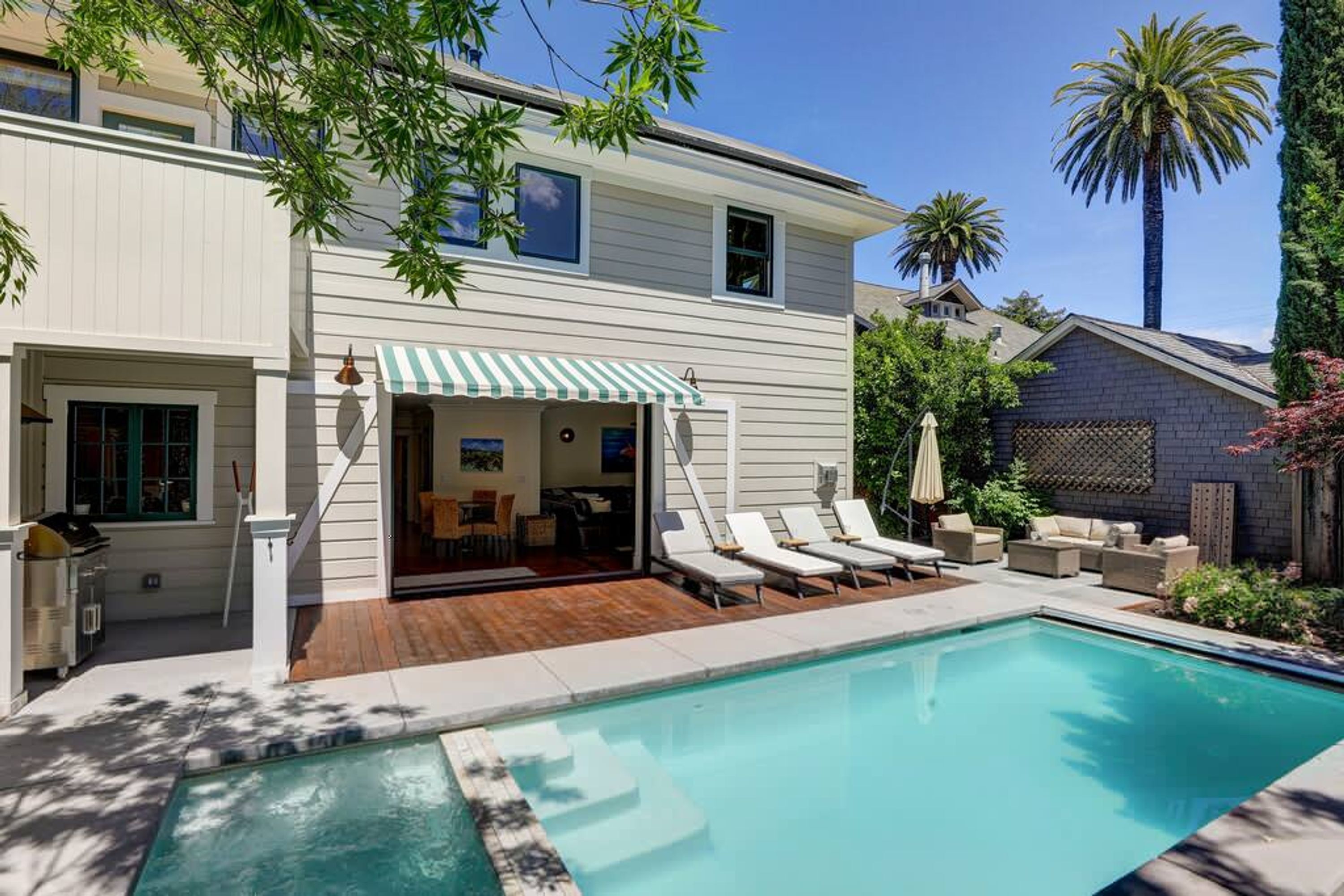 A two-story house with a pool, outdoor seating, and a covered patio.
