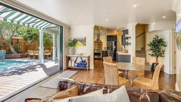 A spacious living area with a large window, a dining table, wicker chairs, and a leather sofa. - Casa Rosa in St Helena (St. Helena)