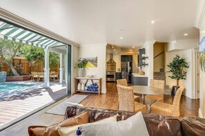 A spacious living area with a large window, a dining table, wicker chairs, and a leather sofa. - Casa Rosa in St Helena (St. Helena)