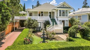 A two-story house with a front porch, a small garden with a fountain, and a visible garage. - Casa Rosa in St Helena (St. Helena)