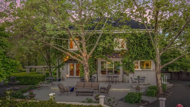 A courtyard with outdoor seating, a pergola, and a house with large windows.