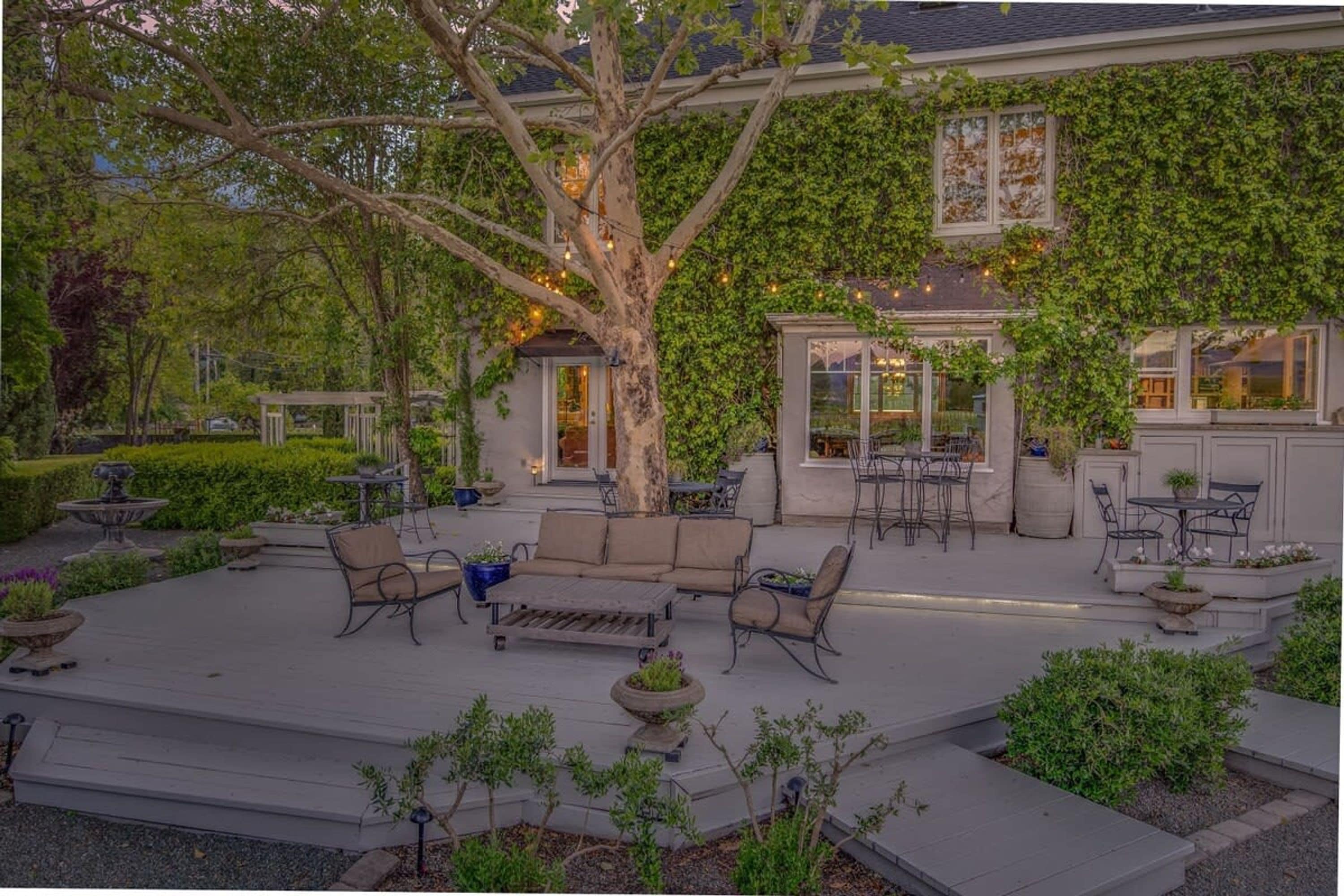 Un patio cubierto con mobiliario exterior, una pérgola y un comedor con vista a la casa.
