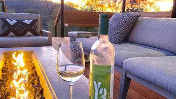 A wooden deck with a fire feature, a glass of white wine, and a bottle of wine.