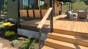 Et moderne hus med træterrasse, udendørs møbler og en overdækket patio.