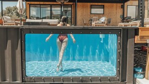 En pool med udsigt til en moderne bygning og udendørs siddepladser.