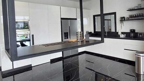 A modern kitchen with sleek black countertops, white cabinets, and a glossy black marble floor. - Casa Black and White. Vista al Mar  (Las Galeras)