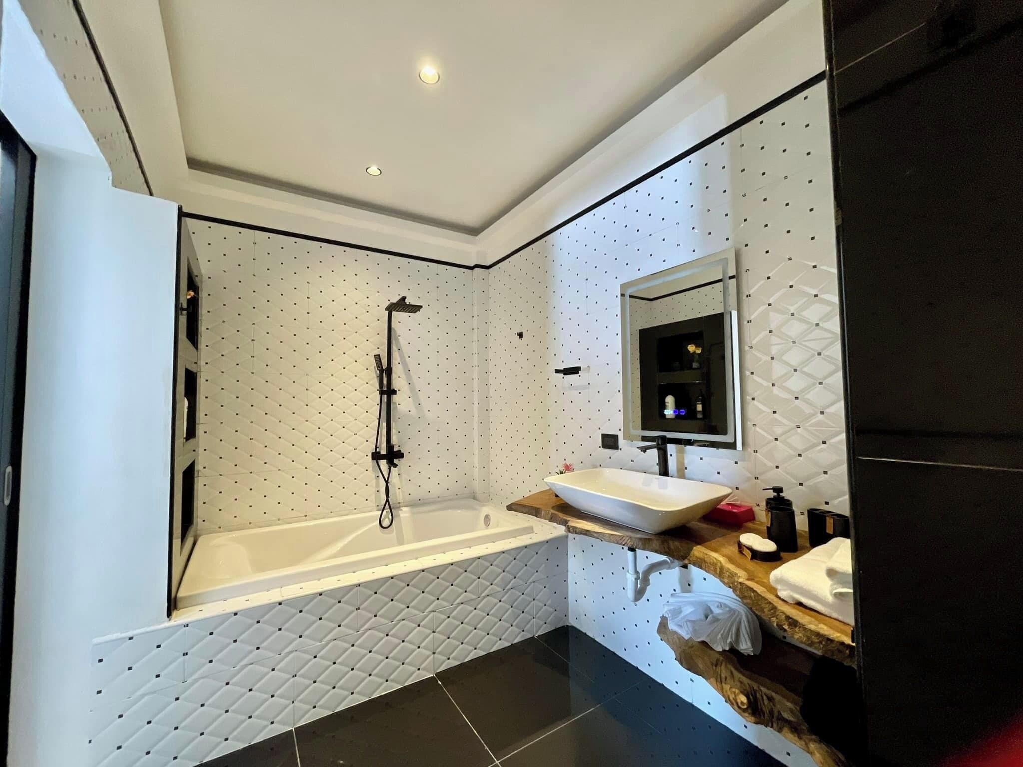 Un bagno moderno con una vasca freestanding, un grande specchio e un mobile lavabo con lavandino e piano.
