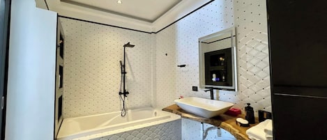 Un bagno moderno con una vasca freestanding, un grande specchio e un mobile lavabo con lavandino e piano.