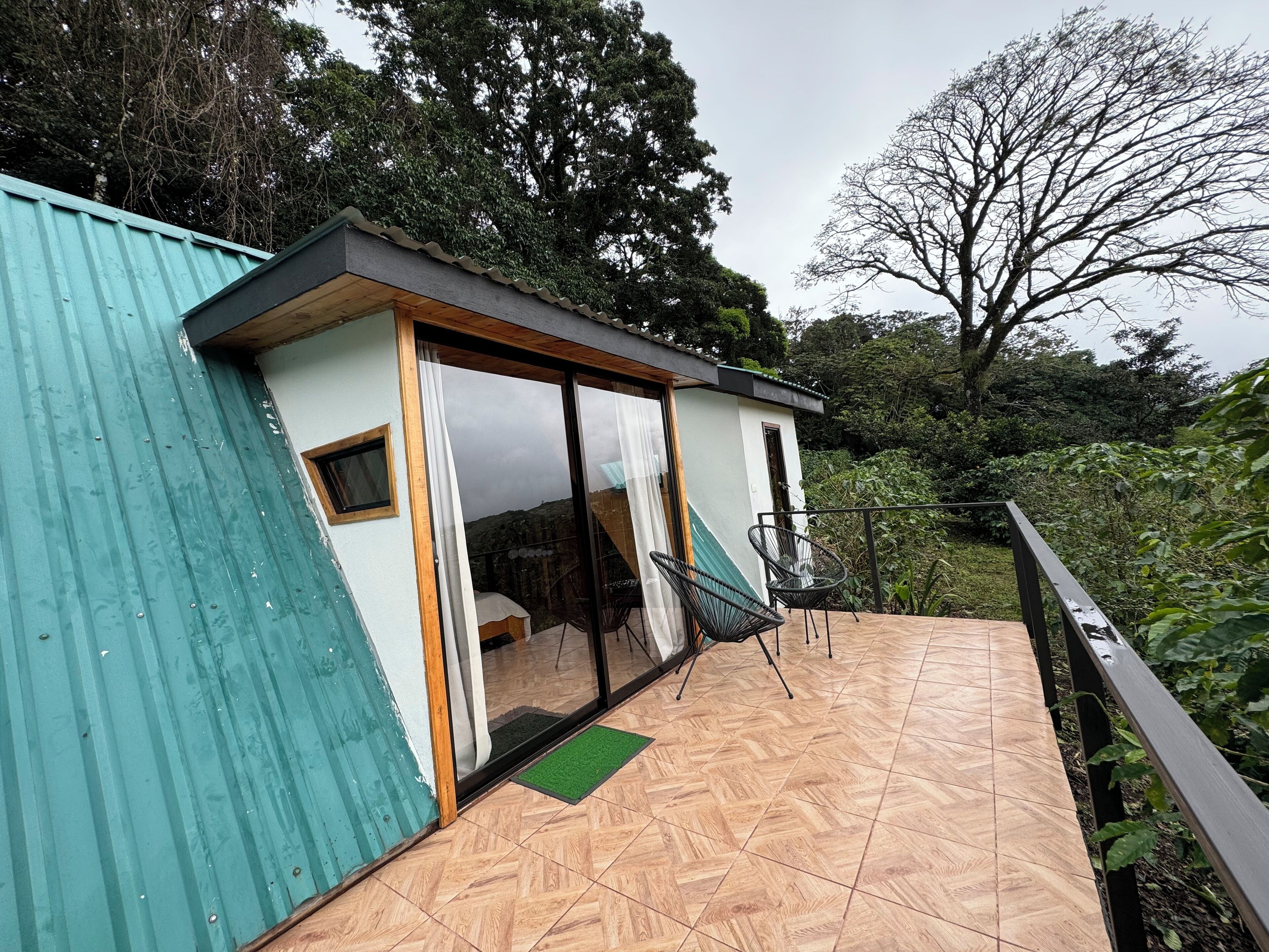 Una casa moderna con balcón, un ventanal pequeño y una puerta.